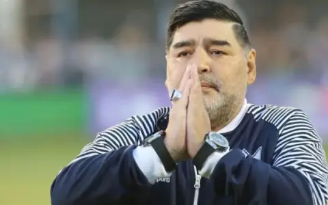 Diego Maradona na co zmarł? Legenda futbolu z dłońmi złożonymi do modlitwy, w charakterystycznej bluzie.