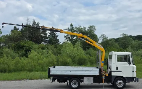Biała ciężarówka z żółtym dźwigiem, gotowa do pracy. Ten Nissan Atleon z pewnością ułatwi transport.
