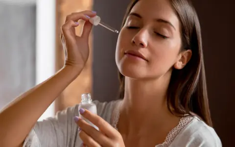 Una mujer aplica serum en su rostro con un gotero. Descubre qué es serum y cómo puede mejorar tu piel.