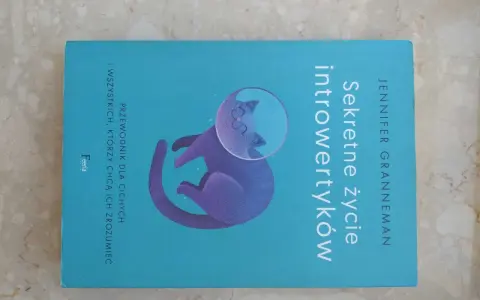 Książka "Sekretne życie introwertyków" z kotem w hełmie kosmicznym. Przewodnik dla cichych i tych, którzy chcą ich zrozumieć.
