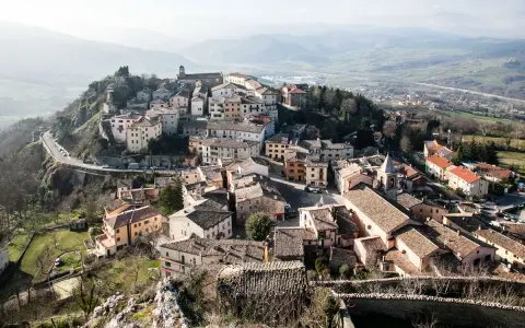 Panoramica di Pennabilli, cosa vedere: borgo medievale arroccato su una collina, con case in pietra, tetti in cotto e una chiesa con campanile.