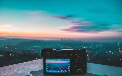Aparat fotograficzny na tle miejskiego krajobrazu o zachodzie słońca. Piękne, kolorowe światło maluje niebo.