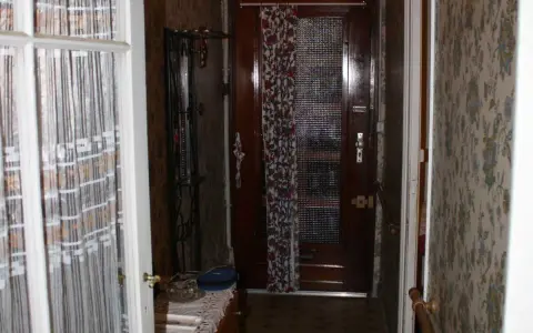 Couloir d'une maison bordeaux typique, avec une porte en bois, un porte-manteau et un papier peint fleuri.