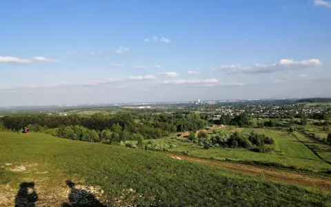 Widok z góry Siewierskiej na zielone pola i lasy, w oddali widać zabudowania i kominy.