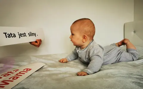 10 tygodniowe dziecko leży na brzuchu, patrząc na napis "Tata jest silny".