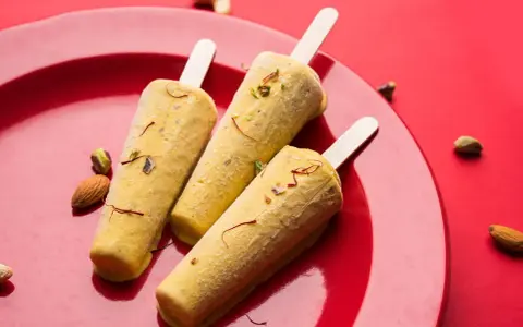Trzy pyszne kulfi na patyku, ozdobione szafranem i orzechami, idealne na letnie orzeźwienie. Ten przepis na kulfi zachwyci każdego!