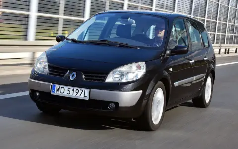 Czarny Renault Scenic 2 jedzie autostradą. Kierowca w okularach przeciwsłonecznych prowadzi auto.