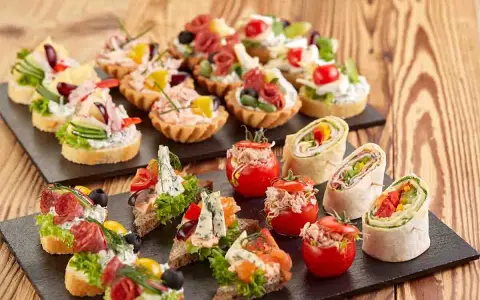 Varietà di tartine, involtini e pomodorini ripieni, perfette per idee aperitivo economico e gustoso.
