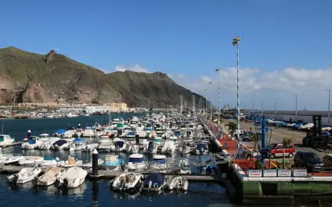Viele Boote liegen im Hafen von Teneriffa vor Anker, im Hintergrund erheben sich grüne Berge.