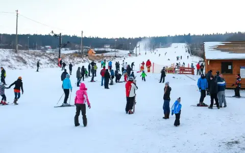 Ludzie jeżdżą na nartach i snowboardach, ciesząc się zimowymi atrakcjami. Warunki na stokach wydają się dobre, śnieg jest obecny, a pogoda sprzyja aktywnościom na świeżym powietrzu.