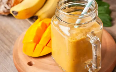 Słoneczny koktajl zamiast śniadania: gęsty, pomarańczowy napój z mango i bananów w słoiku, gotowy do wypicia.
