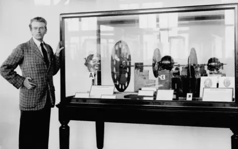 John Logie Baird prezentuje swój wynalazek – pierwszy telewizor na świecie. W gablocie widać dyski Nipkow i silniki.