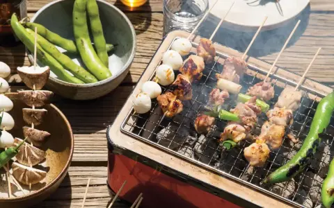 Grillowane **yakitori** z kurczakiem i warzywami, obok miska fasolki i grzybów na patyczkach.