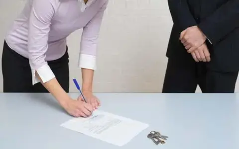Une femme signe un document, peut-être un passage expert assurance habitation, tandis que des clés reposent sur la table.