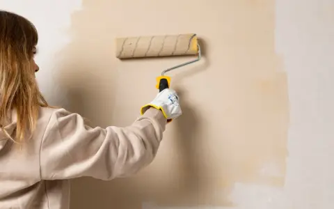 Persona aplicando pintura con rodillo, un truco para pintar sin cinta de carrocero y lograr bordes perfectos.