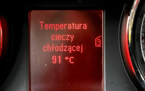 Wyświetlacz pokazuje temperaturę płynu chłodniczego: 91°C. Obok widać fragmenty wskaźników.