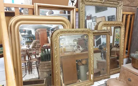 Plusieurs miroirs dorés, certains avec des cadres ornés, sont alignés. Comment reconnaître un miroir Napoléon III ? Cherchez les moulures riches et les détails sculptés.