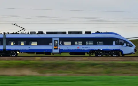 Pociąg PKP Intercity w ruchu, z widocznymi oknami i logo przewoźnika.