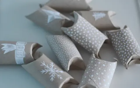 En adventskalender av toarullar, dekorerade med vita julmotiv som snöflingor och stjärnor. Perfekt för att skapa egna små överraskningar.