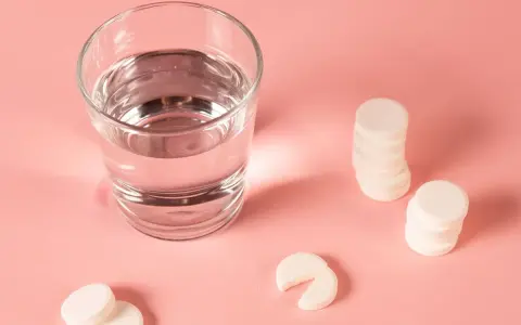 Ein Glas Wasser und Magnesium-Brausetabletten auf rosa Untergrund. Hilft Magnesium beim Einschlafen?