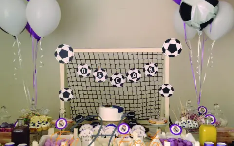 Mesa de chuches del Real Madrid: balones de fútbol, globos, tarta y dulces para una fiesta temática.