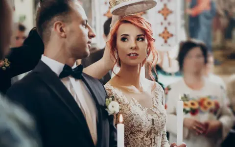 Para ślubna w kościele, z koroną nad głowami. Panna młoda w koronkowej sukni, pan młody w garniturze. W tle goście. Zastanawiasz się, jakie dokumenty do ślubu?