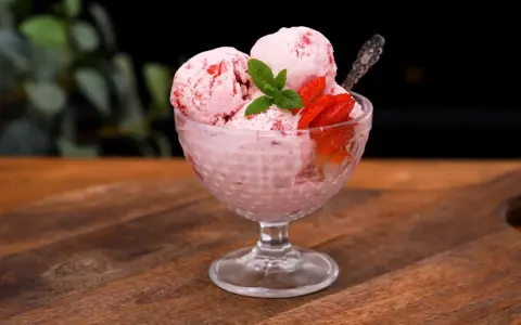 Ljuvlig jordgubbsglass utan glassmaskin i en skål, dekorerad med färska jordgubbar och mynta. Perfekt sommardessert!