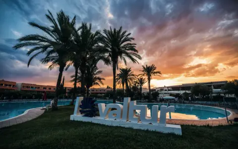 Tramonto infuocato sul Valtur Calabria Otium Resort. Palme e piscina creano un'atmosfera da sogno.