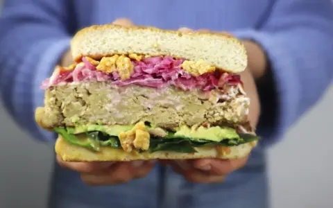 Hamburguesa de pollo con aguacate, col morada y crujientes trozos. ¡Una delicia!