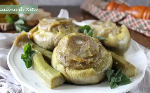 Carciofi alla romana cotti a puntino, teneri e saporiti, guarniti con menta fresca su un piatto bianco.