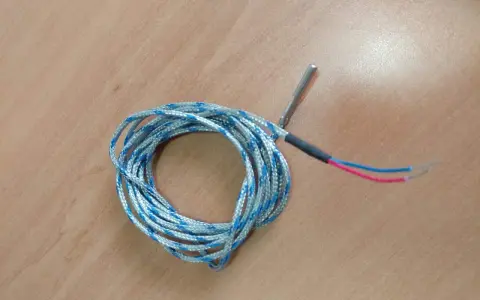 Sonda de temperatura para estufa de pellets, posiblemente indicando un fallo. Cable enrollado con punta metálica y cables rojo y azul.
