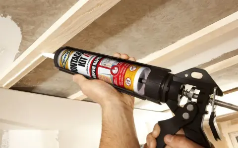Uso di una pistola per colla per fissare il cartongesso a una struttura in legno.
