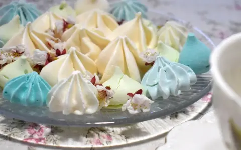 Meringues colorées, comme créées par un robot pâtissier, parsemées de fleurs délicates.