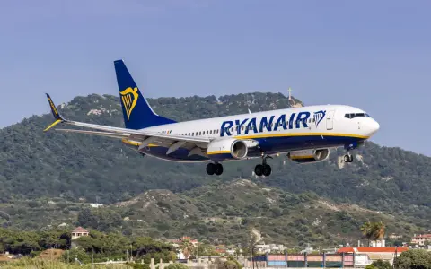 Ryanair ląduje na tle zielonych wzgórz i krzyża na szczycie.