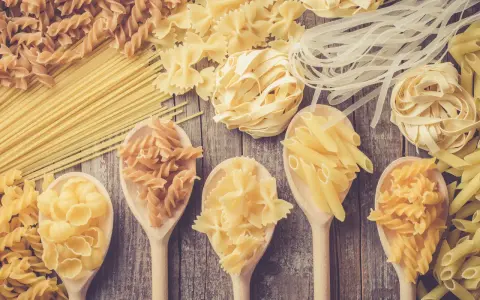 Verschiedene Nudelsorten auf Holzlöffeln und Holzuntergrund. Welche Pasta hat am wenigsten Kalorien? Vielleicht die dünnen Reisnudeln?