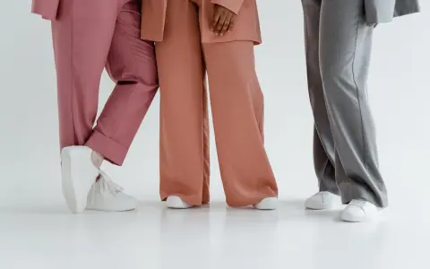 Trzy osoby w eleganckich stylizacjach. Jedna w różowych spodniach, druga w brzoskwiniowych, a trzecia w szarych. Zastanawiasz się, jaka marynarka do szarych spodni pasuje najlepiej?