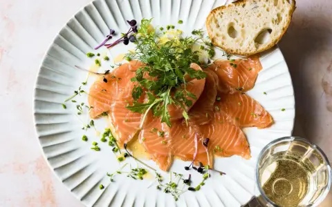 Zarter Saibling, mariniert mit Kräutern und Zitrone, verspricht einen delikaten Geschmack. Dazu ein Stück Brot und ein Glas Weißwein.