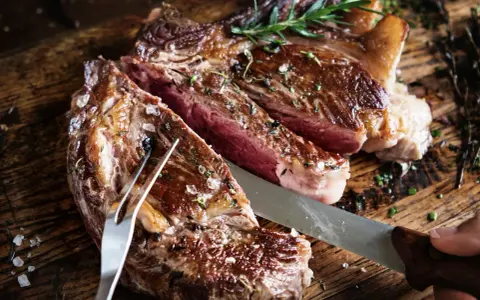 Una succulenta bistecca di manzo, tagliata al sangue, condita con sale grosso e rosmarino, pronta per essere gustata.