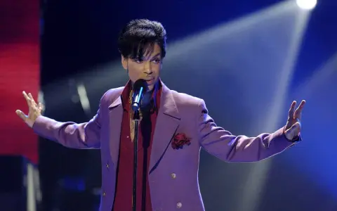 Prince w fioletowej marynarce śpiewa na scenie. Jego śmierć była szokiem dla fanów.
