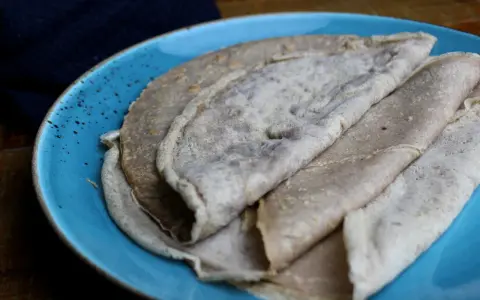 Galettes de sarrasin, naturellement sans gluten, sur une assiette bleue. La farine de blé noir donne cette texture rustique.