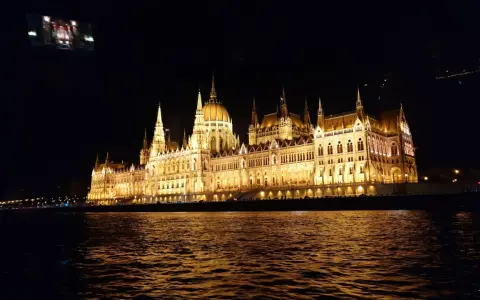 Piękny rejs po Dunaju w Budapeszcie nocą. Parlament lśni w złotej poświacie, odbijając się w falach rzeki.