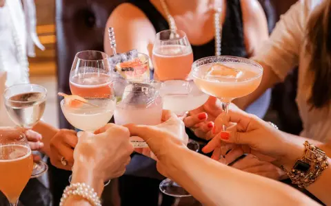 Frauen stoßen mit bunten Cocktails an. Ein fröhlicher Anlass für Day Drinking mit Freundinnen.