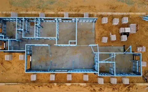 Estructura metálica de una casa en construcción. Se aprecian materiales apilados, listos para el montaje. El precio de hacer un sótano puede variar.