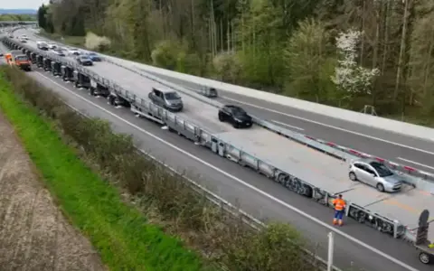 Un puente móvil transporta varios coches por una autopista.