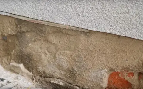Fragment ściany z widoczną warstwą izolacji i miejscem na iniekcję.
