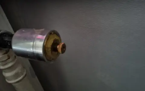 En gammal AGA termostat på ett element. Den kromade delen har en mässingsfärgad ratt.