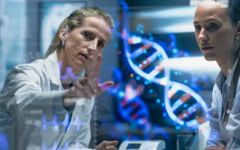 Naukowczyni analizuje strukturę DNA, dyskutując z koleżanką, czy to geny czy wychowanie kształtują człowieka.