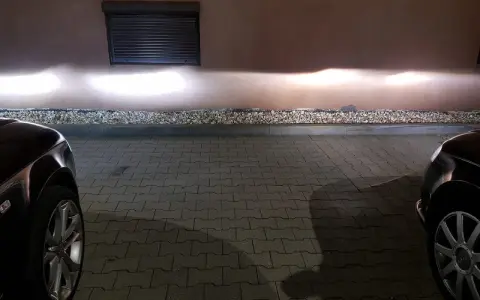 Jasne światła z przodu Audi A4 B6 oświetlają ścianę.