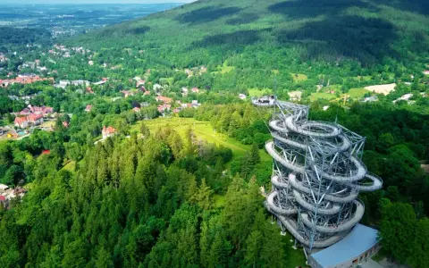 Widok na wieżę widokową w otoczeniu lasów i miasteczka. Idealne miejsce, gdzie w góry można wybrać się na spacer i podziwiać panoramę.