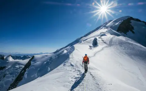 Bergsteiger auf dem Weg zum Gipfel des Mont Blanc. Die Sonne strahlt vom klaren blauen Himmel.